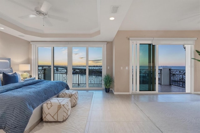 tiled bedroom with access to exterior, a water view, a raised ceiling, and ceiling fan