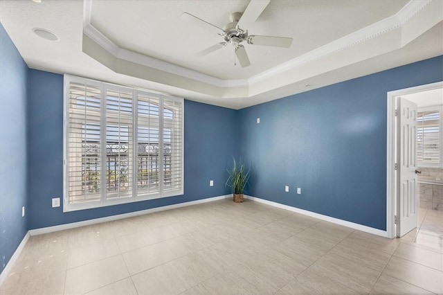 tiled spare room featuring a raised ceiling, a wealth of natural light, crown molding, and ceiling fan