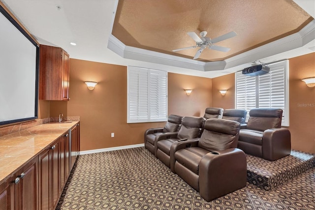 cinema with ceiling fan, sink, a raised ceiling, crown molding, and a textured ceiling