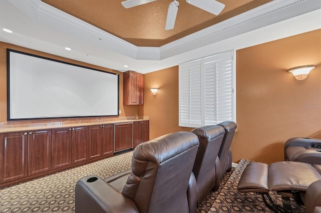 home theater featuring a raised ceiling, ceiling fan, and crown molding