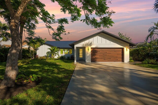 1899 Buccaneer Cir, Sarasota, FL 34231 - view of front facade with concrete driveway, a garage, a yard, and board and batten siding