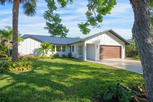 1899 Buccaneer Cir, Sarasota, FL 34231 - view of front of home featuring an attached garage, concrete driveway, board and batten siding, and a metal roof