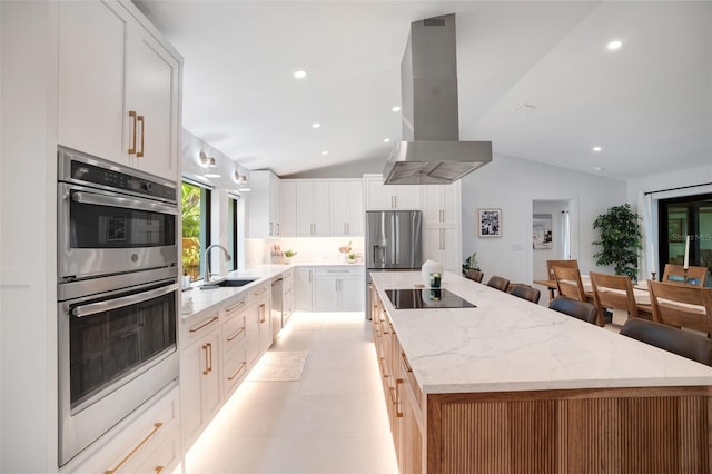 kitchen featuring island exhaust hood, stainless steel appliances, a spacious island, white cabinetry, and lofted ceiling