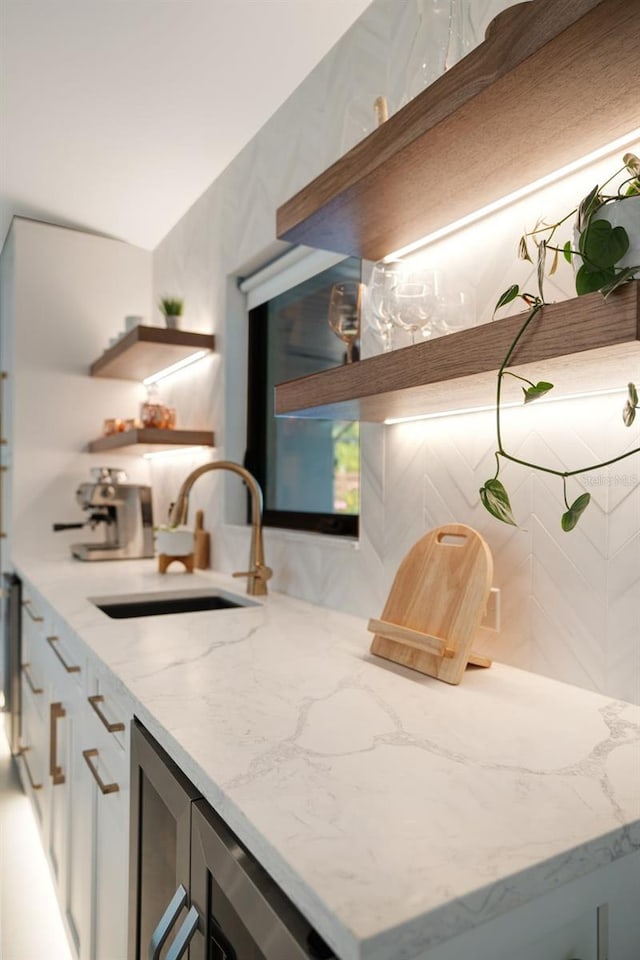 interior space with backsplash, light stone countertops, and sink