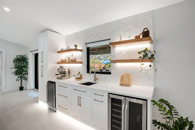 bar with backsplash, white cabinets, sink, wine cooler, and light stone countertops