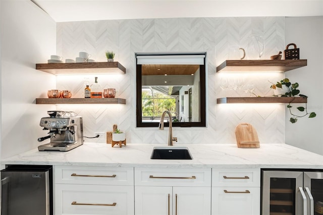 bar with light stone countertops, white cabinetry, beverage cooler, stainless steel fridge, and decorative backsplash