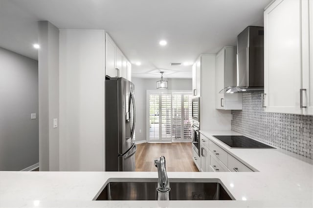 kitchen featuring backsplash, stainless steel appliances, light stone counters, white cabinets, and wall chimney exhaust hood