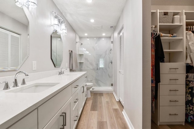 bathroom featuring toilet, a textured ceiling, vanity, a shower with door, and hardwood / wood-style flooring