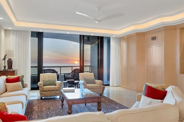 living room with a tray ceiling and ceiling fan