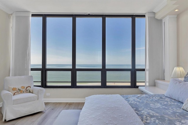 bedroom featuring light hardwood / wood-style floors, a water view, and crown molding