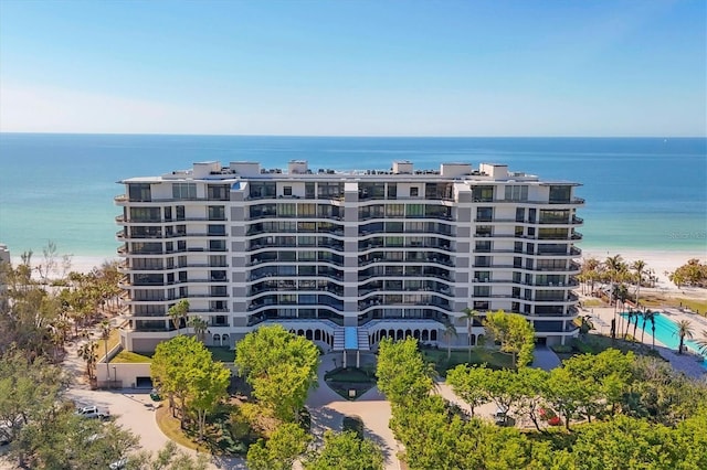 view of building exterior featuring a water view and a beach view