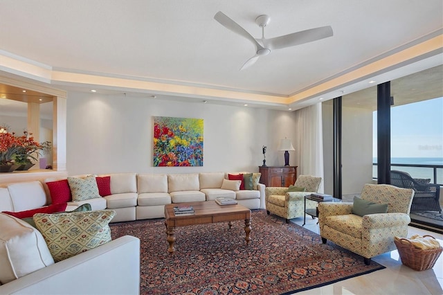 living room featuring ceiling fan, expansive windows, and a water view