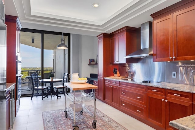 kitchen featuring light stone countertops, wall chimney exhaust hood, backsplash, pendant lighting, and black electric cooktop