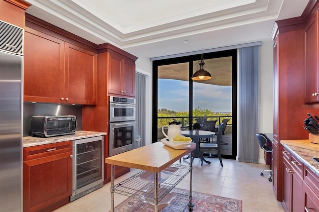 kitchen with beverage cooler, a raised ceiling, light stone counters, decorative light fixtures, and appliances with stainless steel finishes