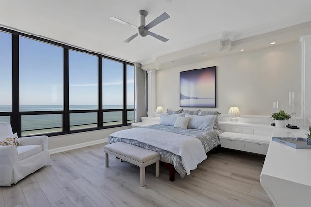 bedroom with a water view, light hardwood / wood-style flooring, and ceiling fan