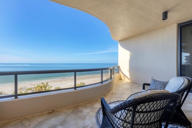 balcony with a water view and a view of the beach