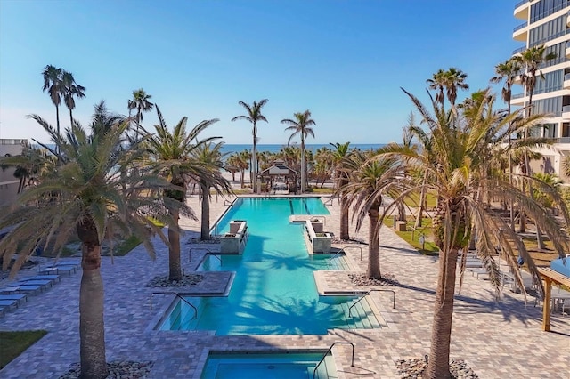 view of pool featuring a water view and a patio