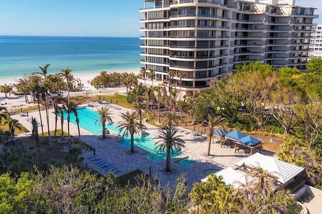 view of pool featuring a patio area, a water view, and a beach view