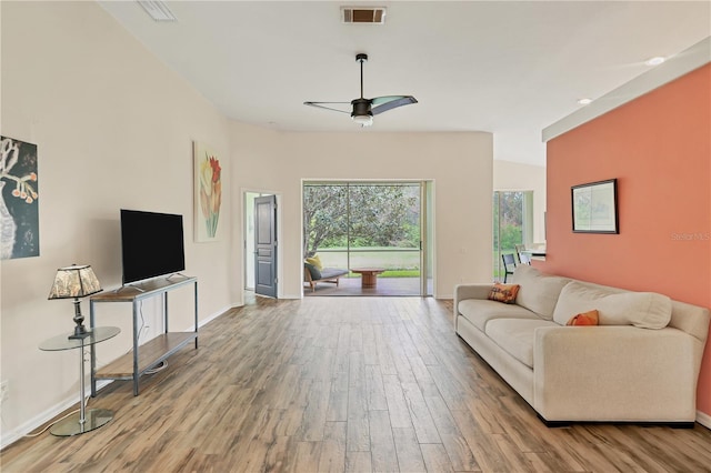 living room with ceiling fan, light hardwood / wood-style floors, and lofted ceiling