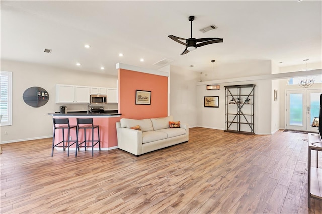 living room featuring french doors, ceiling fan with notable chandelier, light hardwood / wood-style flooring, and sink