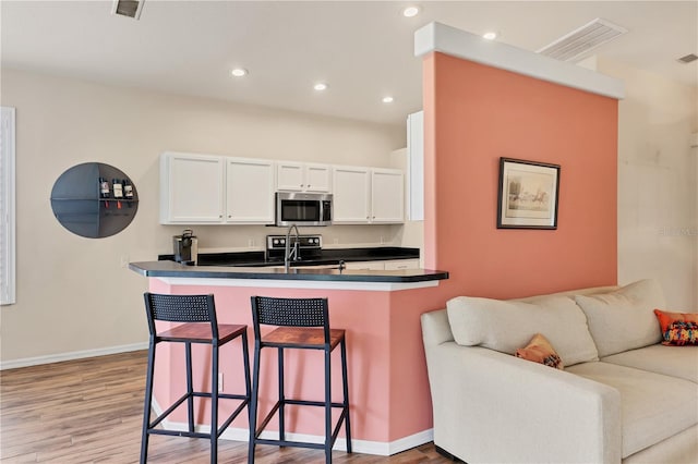 kitchen featuring white cabinets, a breakfast bar, light wood-type flooring, and kitchen peninsula