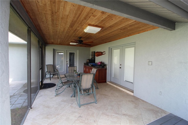 sunroom featuring beamed ceiling, french doors, ceiling fan, and wood ceiling