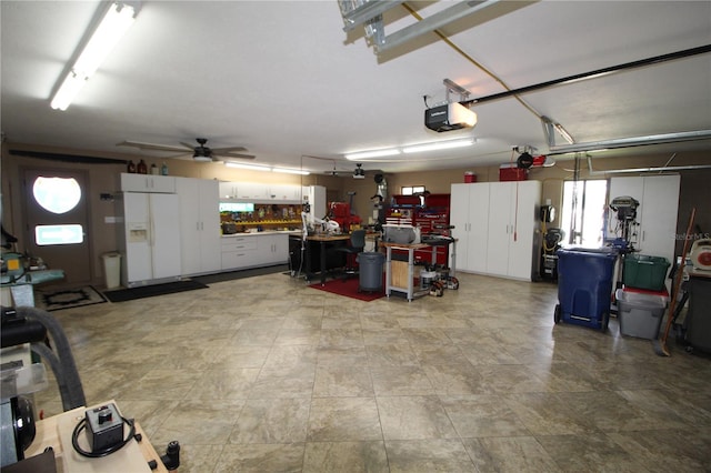 garage featuring white refrigerator with ice dispenser, a workshop area, a garage door opener, and ceiling fan