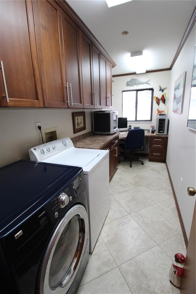 laundry room with cabinets, light tile patterned floors, crown molding, and washing machine and clothes dryer