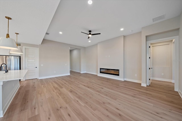 unfurnished living room with light wood-type flooring and ceiling fan