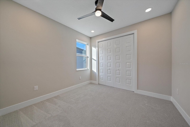 unfurnished bedroom with a closet, light colored carpet, and ceiling fan