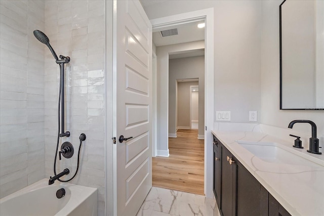 bathroom featuring vanity, wood-type flooring, and tiled shower / bath combo