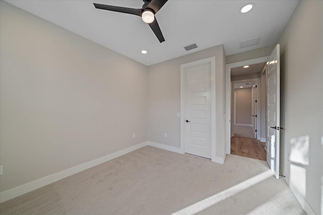 unfurnished bedroom featuring a closet, light colored carpet, and ceiling fan