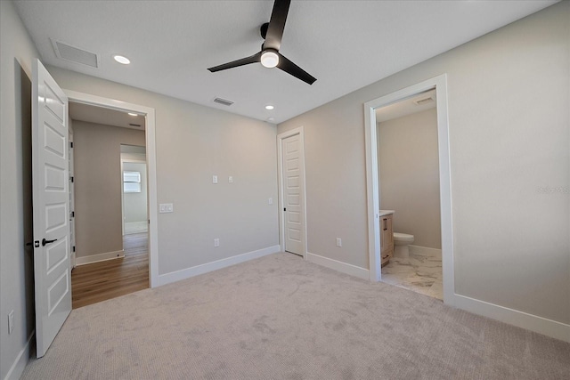 unfurnished bedroom featuring ceiling fan, ensuite bathroom, and light colored carpet