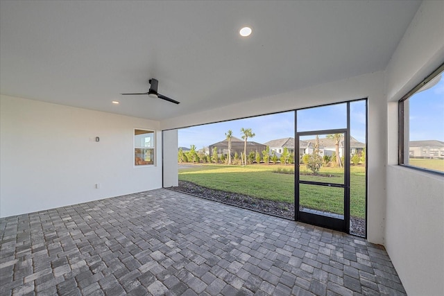 unfurnished sunroom with ceiling fan