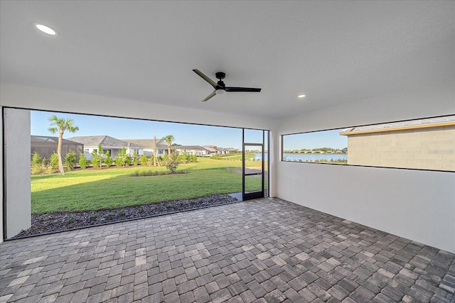 unfurnished sunroom featuring a water view, ceiling fan, and a healthy amount of sunlight