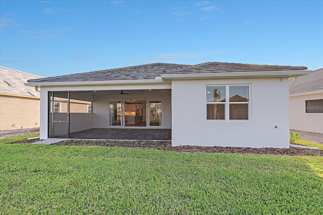 rear view of house featuring ceiling fan, a yard, and a patio