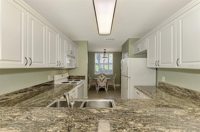 kitchen with dark stone countertops, white cabinetry, sink, and white appliances