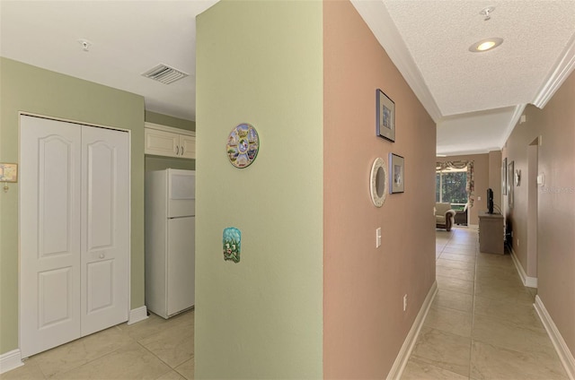 hall featuring light tile patterned floors, a textured ceiling, and ornamental molding