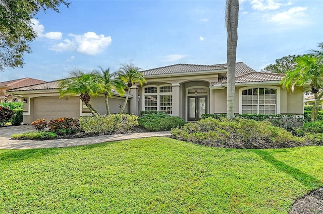 mediterranean / spanish home with a front yard, french doors, and a garage