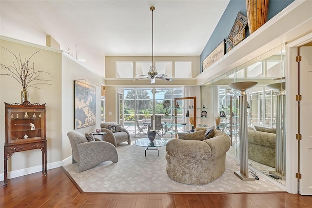 living room with hardwood / wood-style flooring, ceiling fan, and a high ceiling