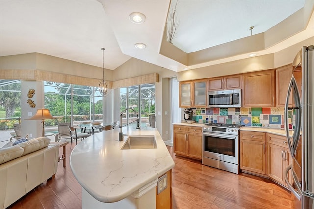 kitchen with a wealth of natural light, hanging light fixtures, an island with sink, and stainless steel appliances