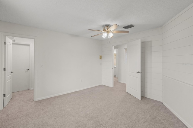 carpeted spare room featuring a textured ceiling and ceiling fan