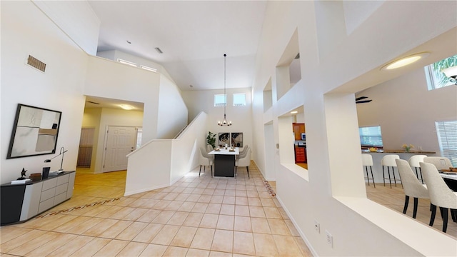 interior space with light tile patterned floors, a towering ceiling, and a wealth of natural light