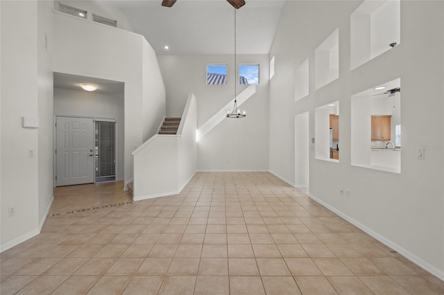 unfurnished living room with light tile patterned floors, a towering ceiling, and ceiling fan