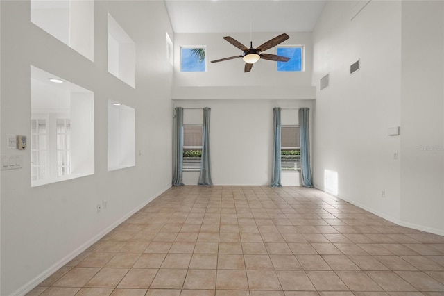 spare room featuring a high ceiling, light tile patterned floors, and ceiling fan