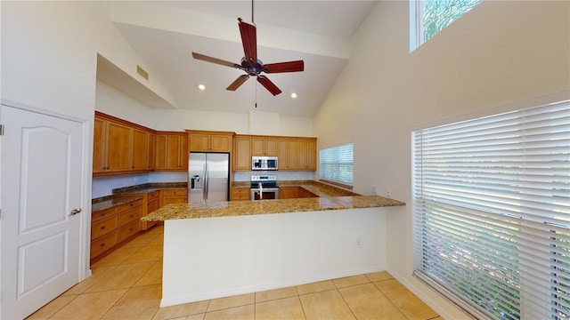 kitchen featuring high vaulted ceiling, appliances with stainless steel finishes, stone countertops, light tile patterned flooring, and kitchen peninsula