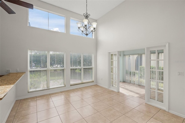 unfurnished dining area with light tile patterned floors, a towering ceiling, and plenty of natural light