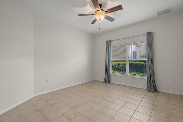 empty room featuring light tile patterned floors, a textured ceiling, and ceiling fan