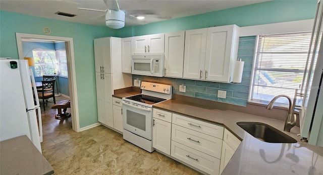 kitchen featuring white cabinets, white appliances, plenty of natural light, and sink