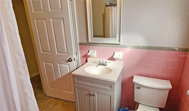 bathroom with tile patterned floors, vanity, toilet, and tile walls